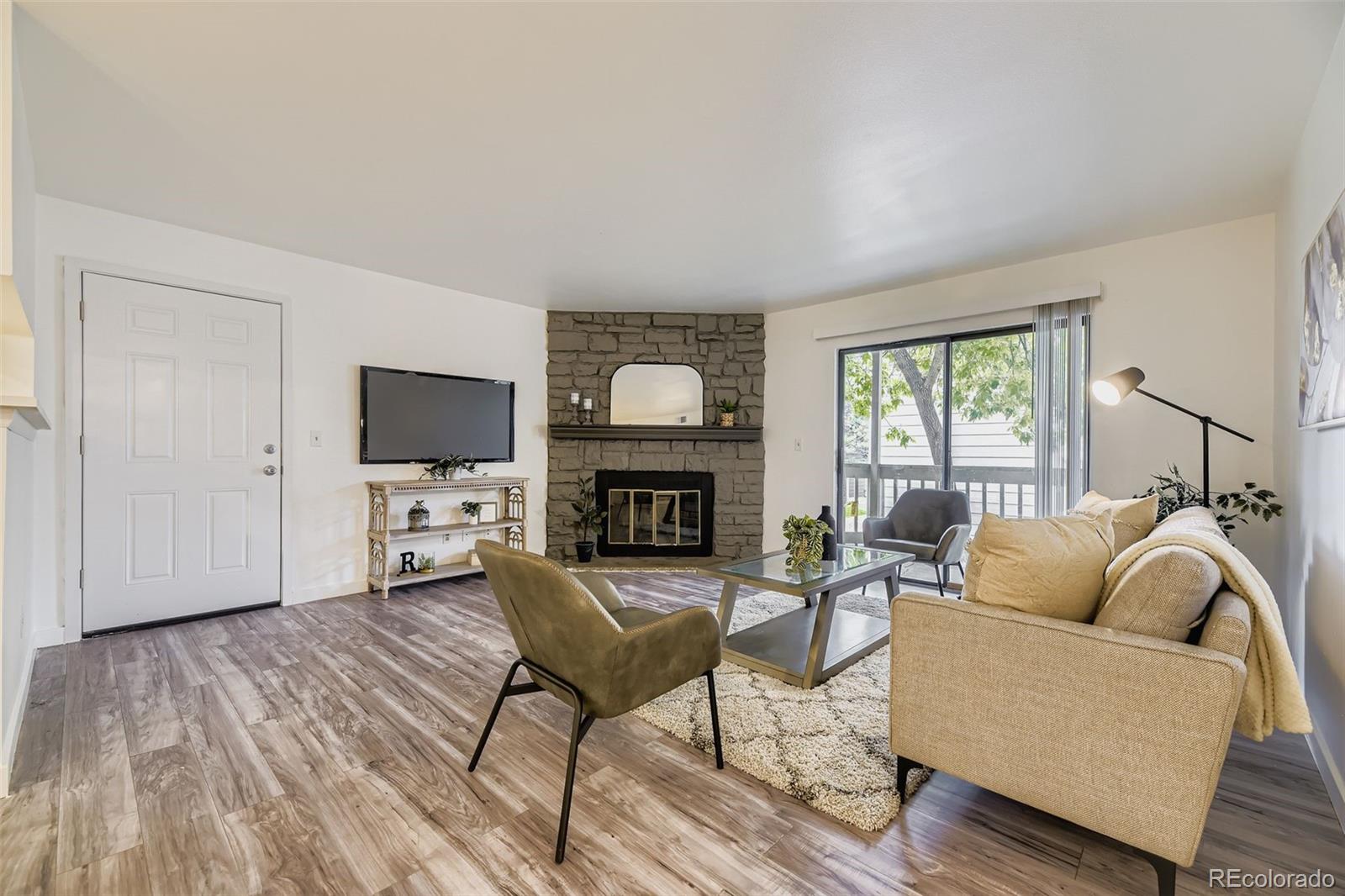 18003 East Ohio Avenue, Unit 102 Aurora, CO 80017 - Photo 2 of 11 a living room with furniture a fireplace and a flat screen tv