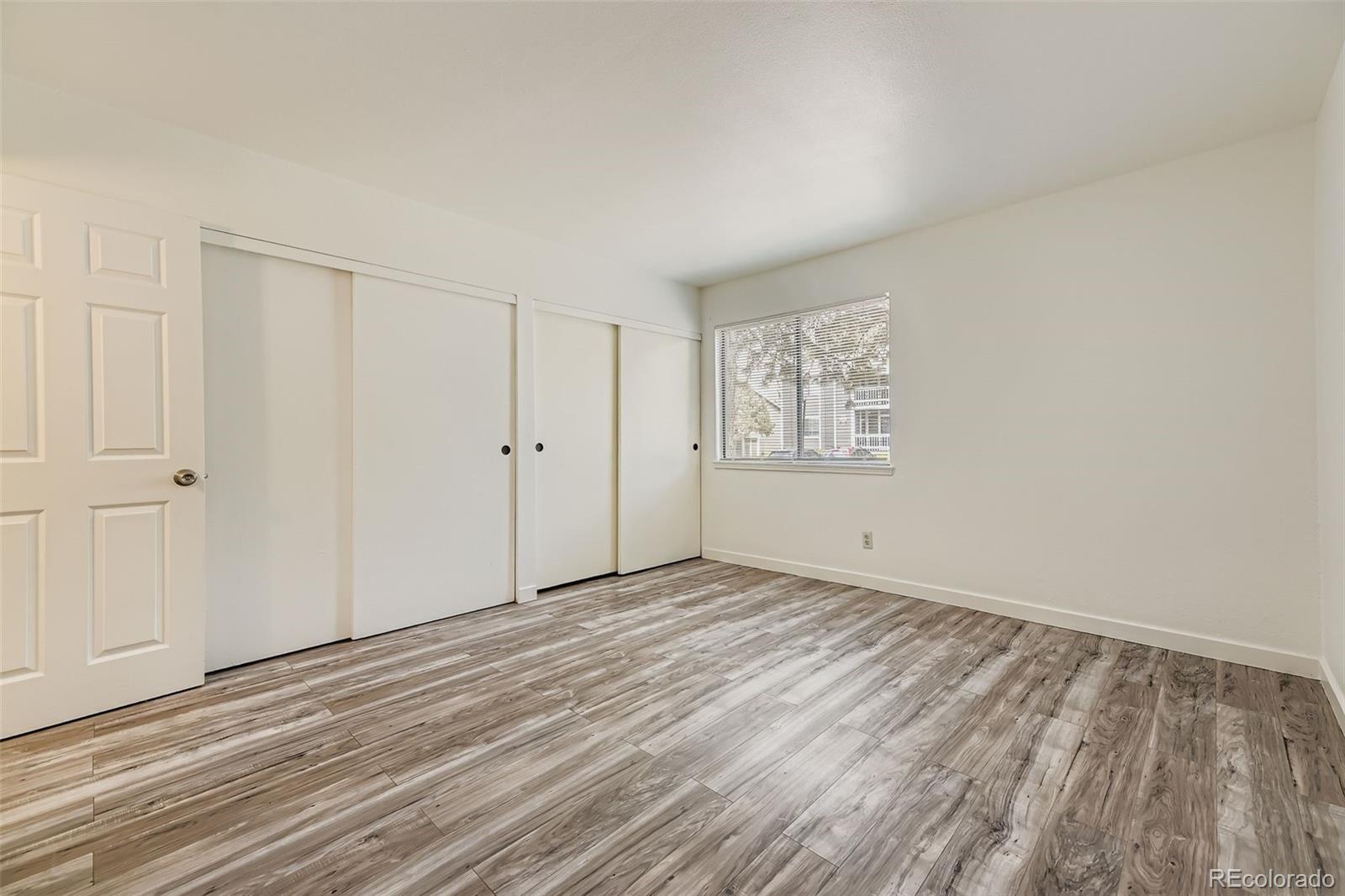 18003 East Ohio Avenue, Unit 102 Aurora, CO 80017 - Photo 6 of 11 a view of an empty room with window and wooden floor