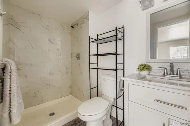 a bathroom with a granite countertop sink toilet mirror and shower
