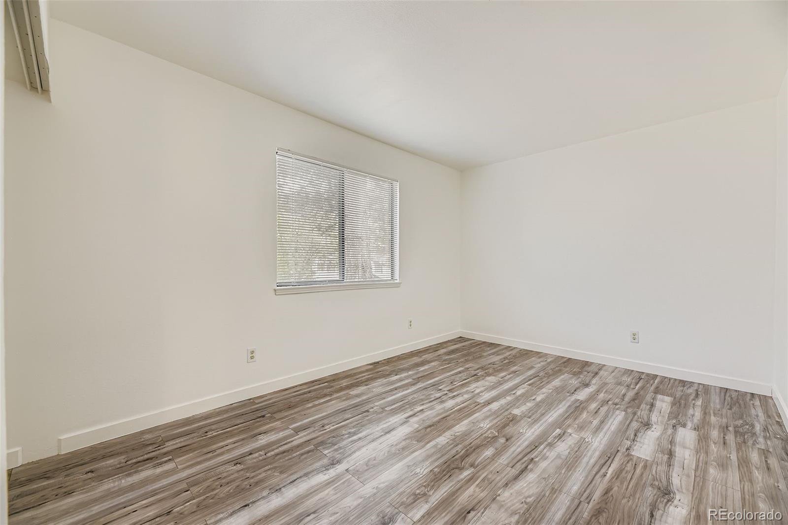18003 East Ohio Avenue, Unit 102 Aurora, CO 80017 - Photo 9 of 11 an empty room with wooden floor and windows