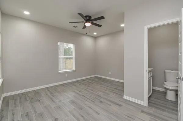 a view of an empty room with a window and wooden floor