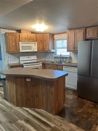 a kitchen with stainless steel appliances granite countertop a sink a stove a refrigerator cabinets and wooden floor