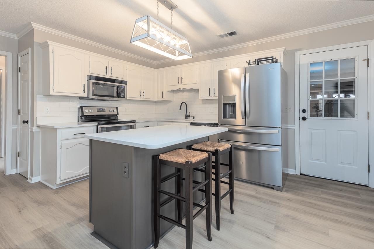 6490 Stone Lake Drive Bartlett, TN 38135 - Photo 8 of 32 a kitchen with stainless steel appliances a table chairs refrigerator and microwave