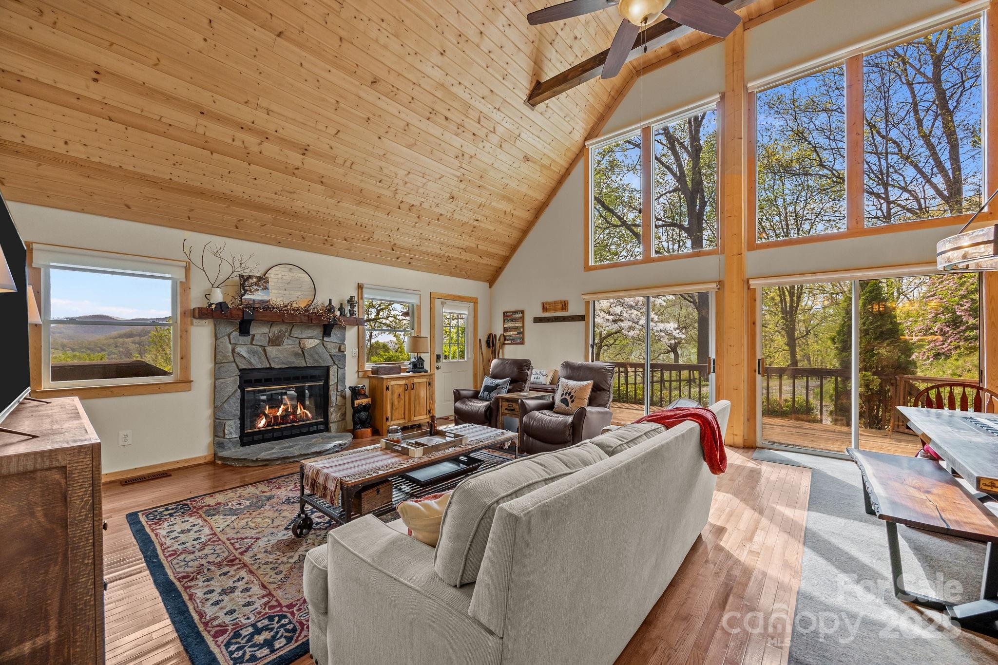 1954 Utah Mountain Road Waynesville, NC 28785 - Photo 16 of 39 a living room with furniture a fireplace and a floor to ceiling window