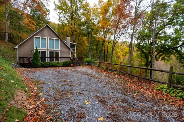 a view of house with a yard and large trees