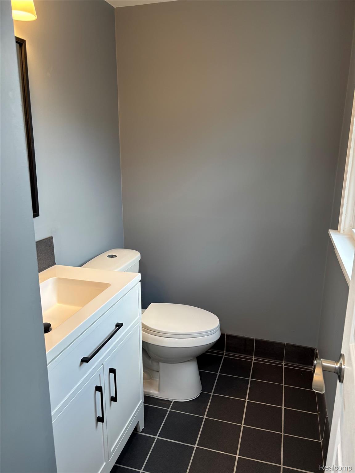 18259 Spring Court South Fraser, MI 48026 - Photo 55 of 60 White vanity with integrated sink, matte black hardware, square tile flooring, and neutral wall paint