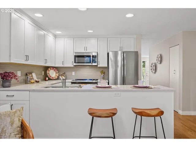 a kitchen with stainless steel appliances a sink a stove a refrigerator and cabinets