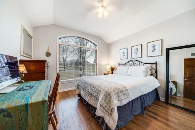 a bedroom with bed a flat tv screen and a dresser