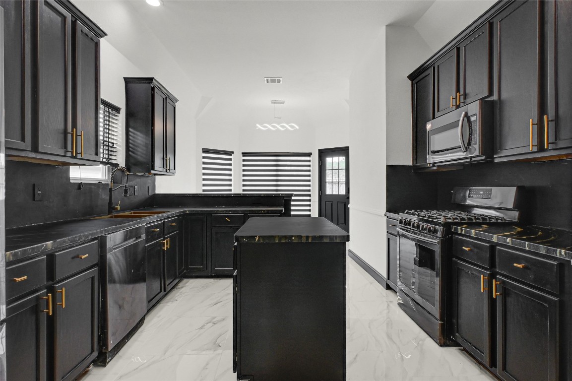 11915 Helene Court Pinehurst, TX 77362 - Photo 6 of 33 a kitchen with stainless steel appliances granite countertop a stove top oven a sink dishwasher and a refrigerator with wooden cabinets