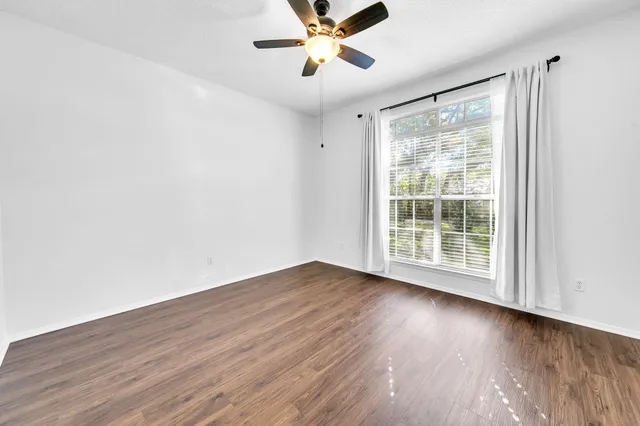 an empty room with wooden floor and a ceiling fan