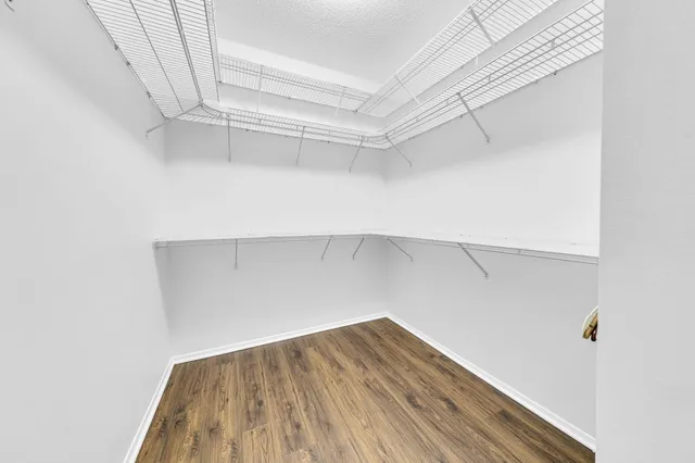 a view of an empty room with wooden floor fireplace and a window