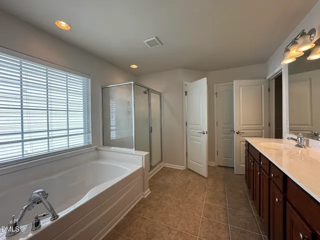 a spacious bathroom with a tub a sink and mirror