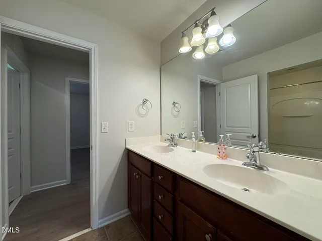 a bathroom with double vanity sinks a vanity a lamp and a mirror