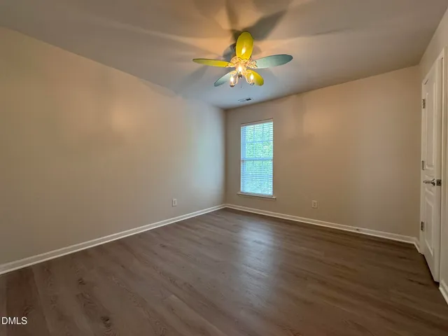 a view of an empty room with a window and wooden floor