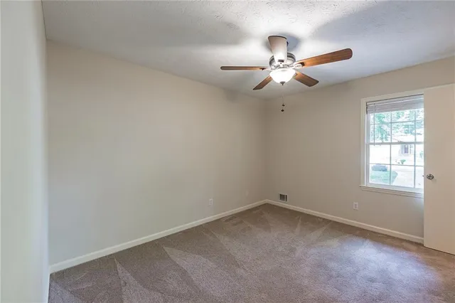 an empty room with closet and ceiling fan