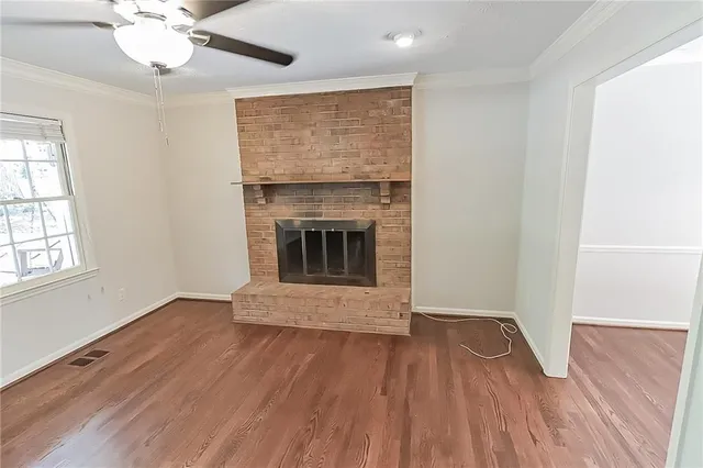 an empty room with wooden floor fireplace and windows