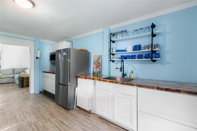 a kitchen with stainless steel appliances granite countertop a sink dishwasher and a refrigerator with wooden floor
