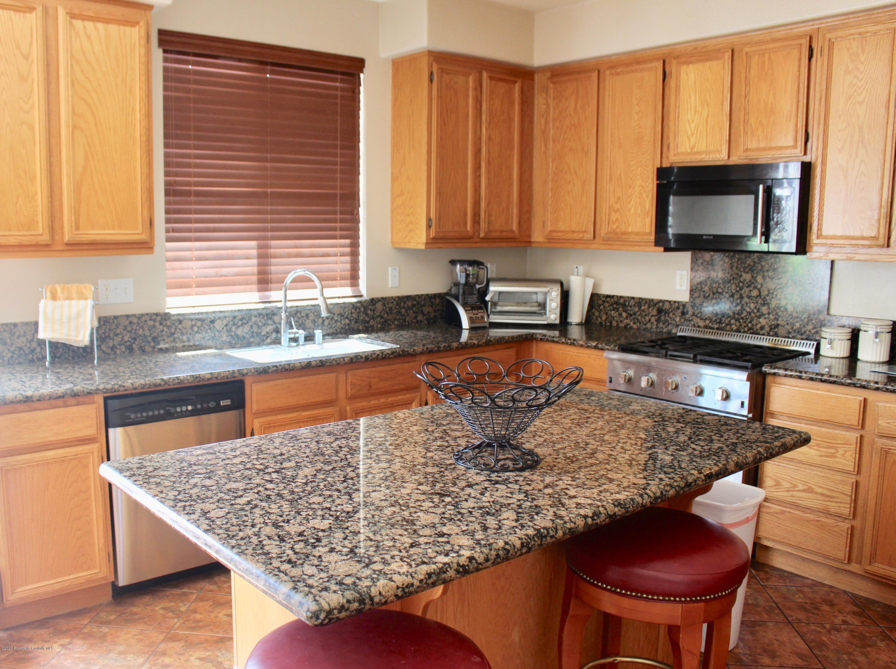 4345 Cloudywing Road Hemet, CA 92545 - Photo 7 of 18 a kitchen with stainless steel appliances granite countertop a sink a microwave and wooden cabinets
