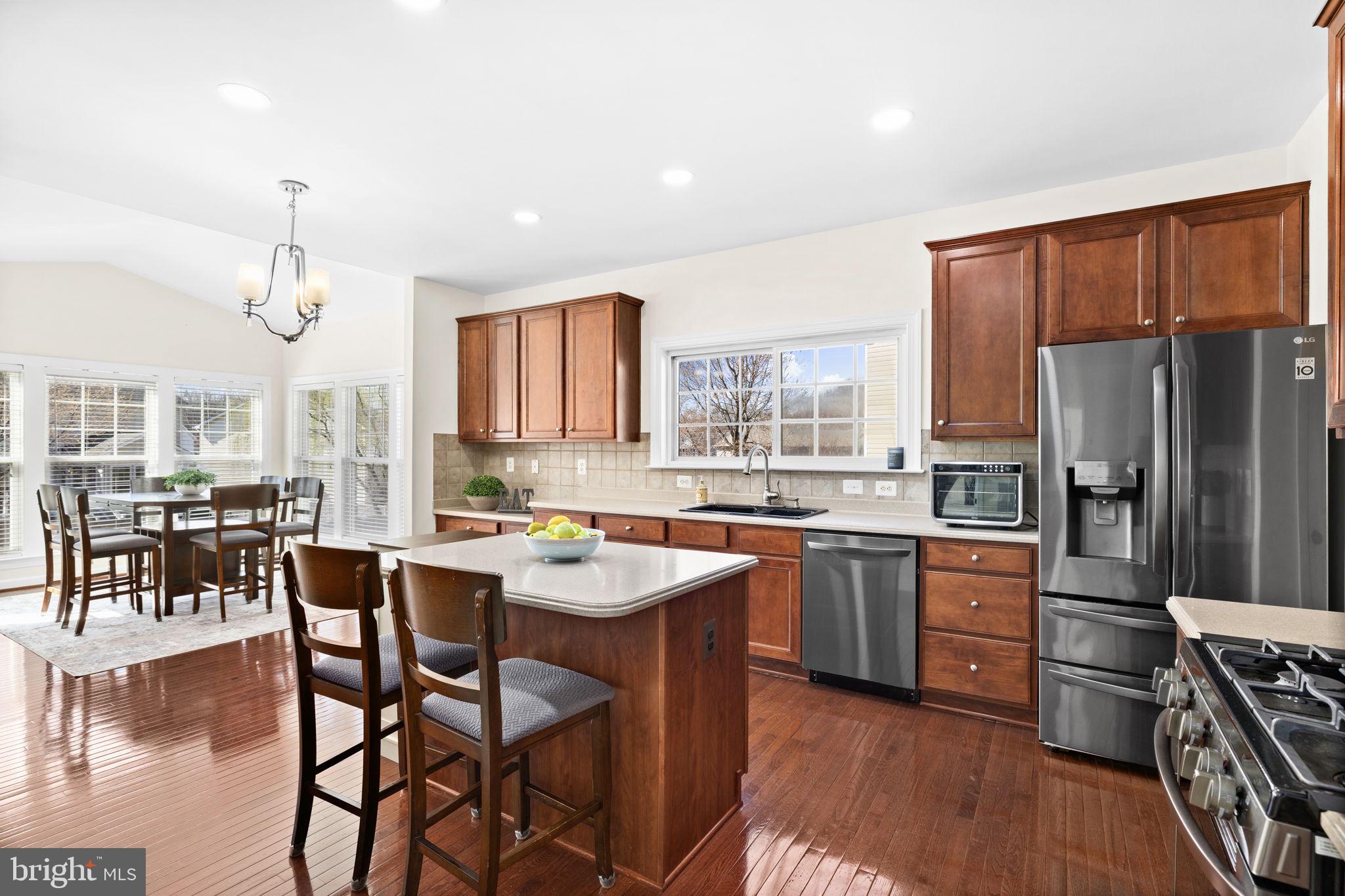 4185 Agency Loop Triangle, VA 22172 - Photo 17 of 46 a kitchen with stainless steel appliances granite countertop a stove top oven a refrigerator a sink and a dining table with wooden floor