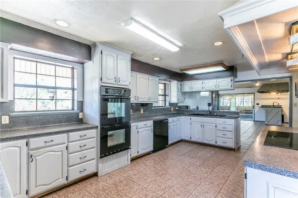 a large kitchen with stainless steel appliances granite countertop a large stove a sink dishwasher and white cabinets with wooden floor