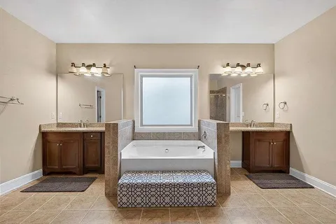 a bathroom with a tub a sink and a mirror