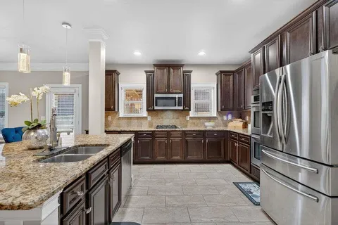 a kitchen with stainless steel appliances granite countertop a sink refrigerator and cabinets