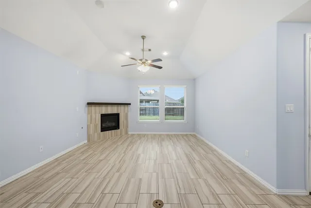 a view of an empty room with wooden floor fireplace and a window