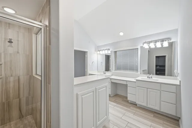 a large white bathroom with a sink and mirror with shower