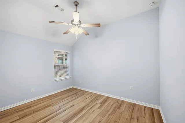 an empty room with wooden floor fan and windows