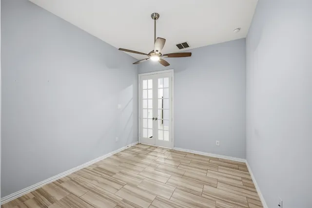 a view of empty room with wooden floor and fan