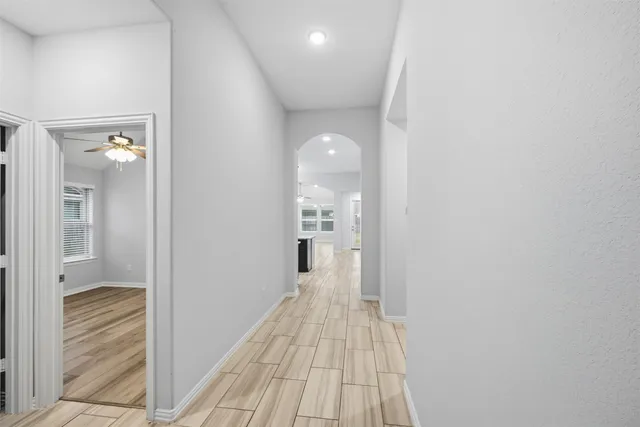 a view of a hallway with wooden floor and a bathroom
