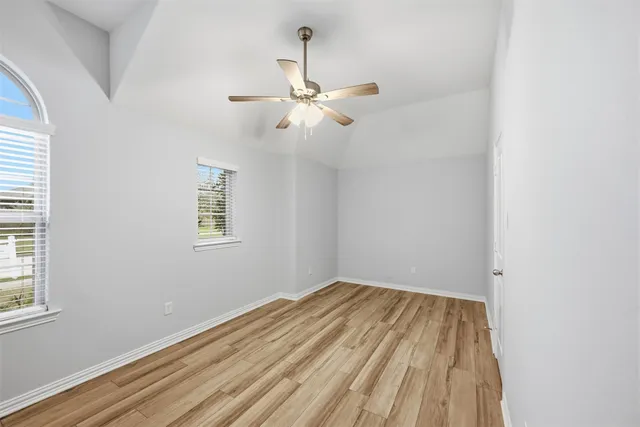an empty room with a window and ceiling fan