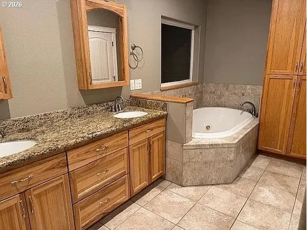 a bathroom with a granite countertop bathtub sink and mirror