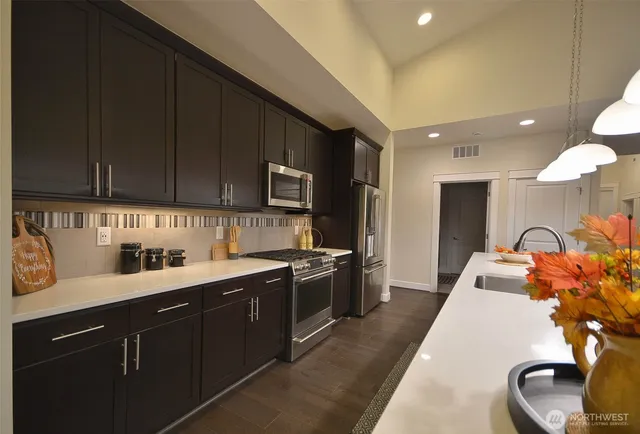 a kitchen with stainless steel appliances granite countertop a sink a stove and cabinets