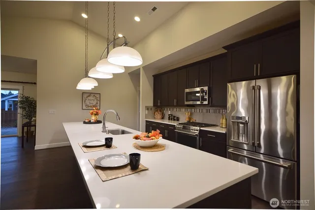 a kitchen with a refrigerator a stove a sink and a dining table with wooden floor