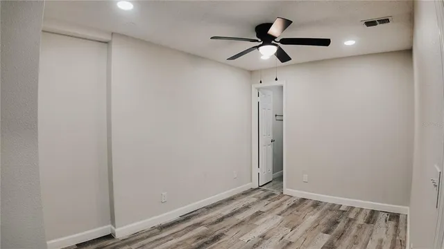 a view of room with wooden floor and a ceiling fan