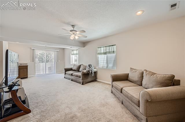 12510 Motley Road Peyton, CO 80831 - Photo 25 of 36 Living room featuring a textured ceiling, ceiling fan, and light colored carpet