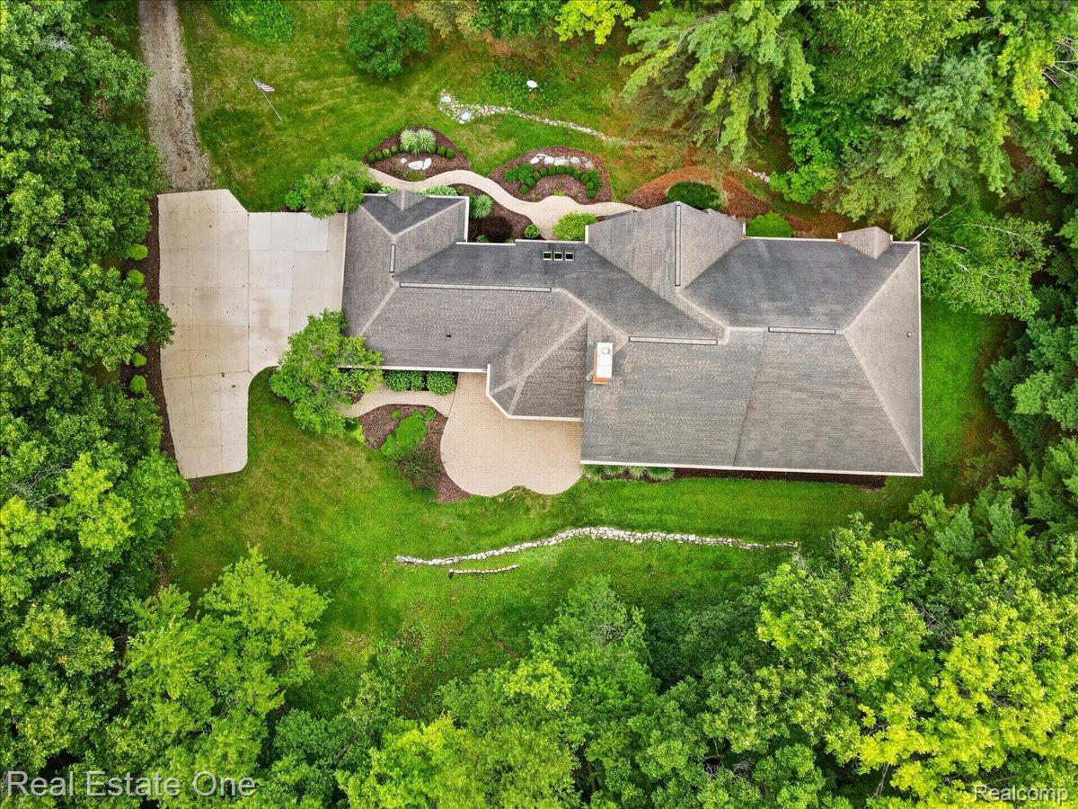 425 Courtney Road Leonard, MI 48367 - Photo 73 of 89 Spacious property featuring a large concrete driveway, extensive landscaping with manicured lawns, mature trees, and a multi-level asphalt shingle roof