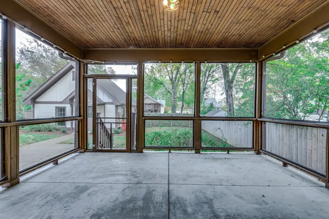 a view of a brick house with a yard plants and large tree