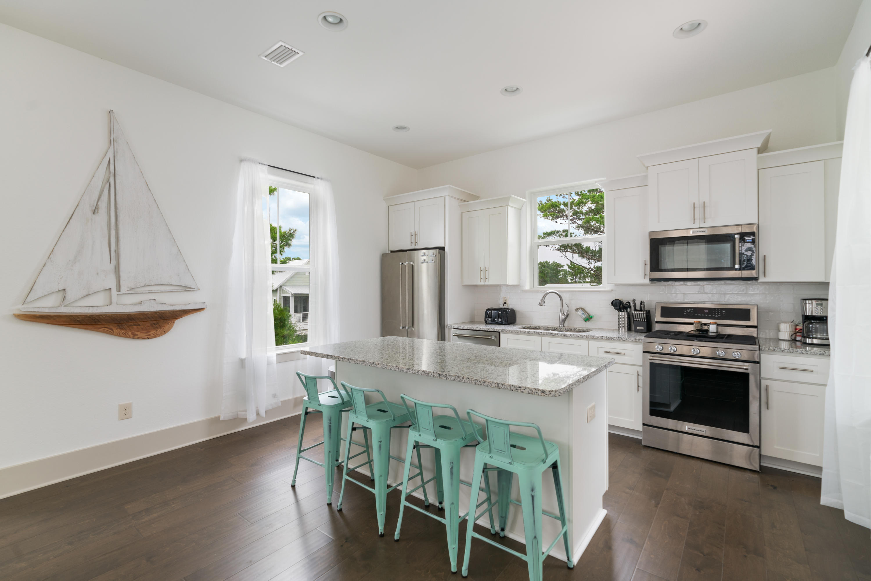 275 Gulfview Circle Santa Rosa Beach, FL 32459 - Photo 4 of 47 a kitchen with stainless steel appliances granite countertop a stove a sink a microwave a refrigerator and white cabinets with wooden floor