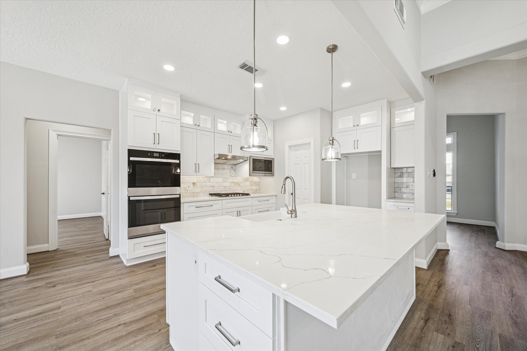 5437 Edgewater Court Willis, TX 77318 - Photo 7 of 29 a large kitchen with kitchen island a stove a sink a refrigerator and white cabinets with wooden floor