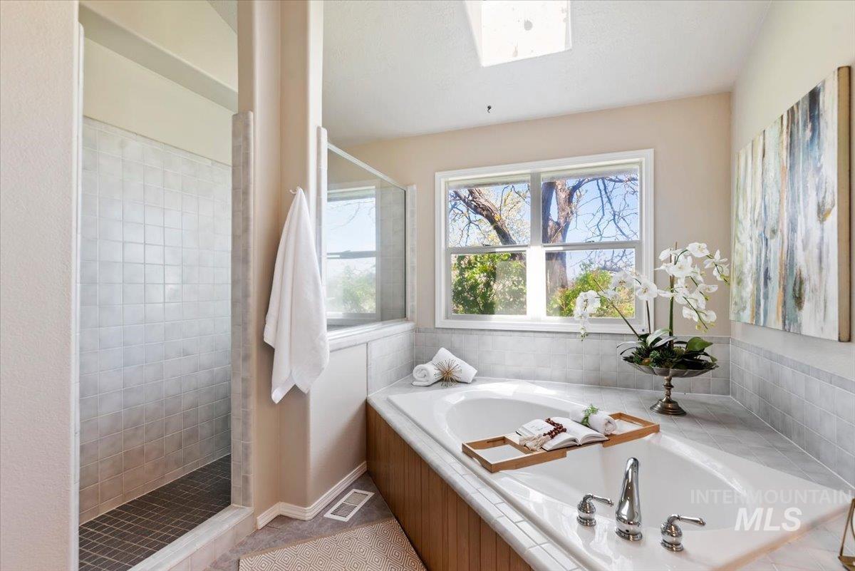 147 East Indian Crk Road Boise, ID 83716 - Photo 17 of 43 Built-in soaking tub with chrome fixtures, surrounded by a light-toned tile deck and wood-finish paneling