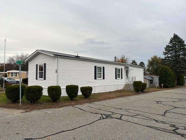 735 Memorial Drive, Unit 40 Chicopee, MA 01020 - Photo 2 of 20 a view of a white house with a barbeque and lawn chairs under an umbrella