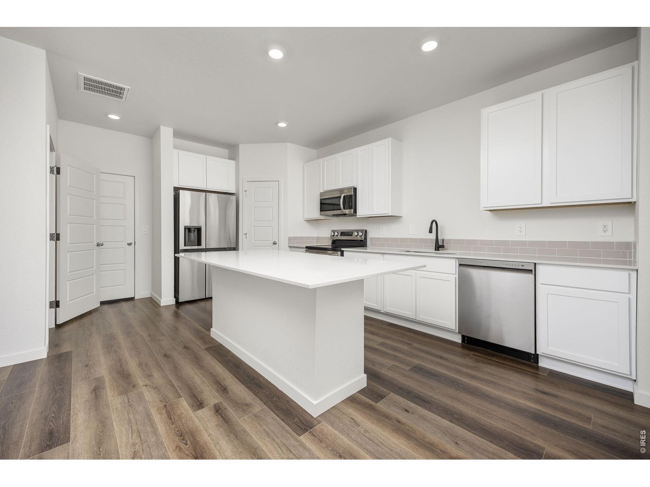 315 Condor Way Johnstown, CO 80534 - Photo 8 of 25 a kitchen with white cabinets and stainless steel appliances