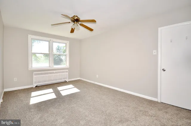 an empty room with windows and ceiling fan
