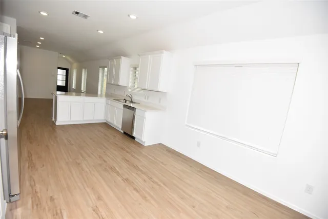 a view of a kitchen with kitchen island a sink wooden floor and stainless steel appliances