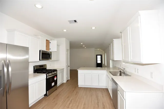 a kitchen with a sink a microwave a refrigerator and cabinets