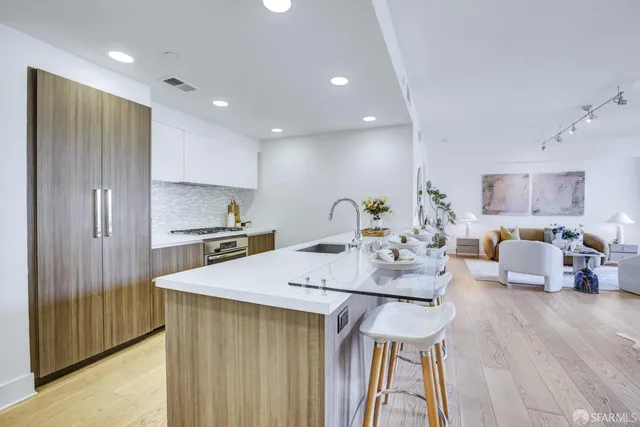 a open kitchen with stainless steel appliances granite countertop a sink dishwasher and a refrigerator with wooden floor