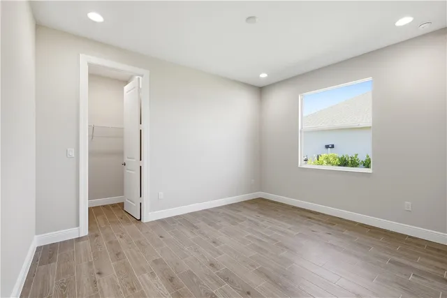 an empty room with wooden floor and window