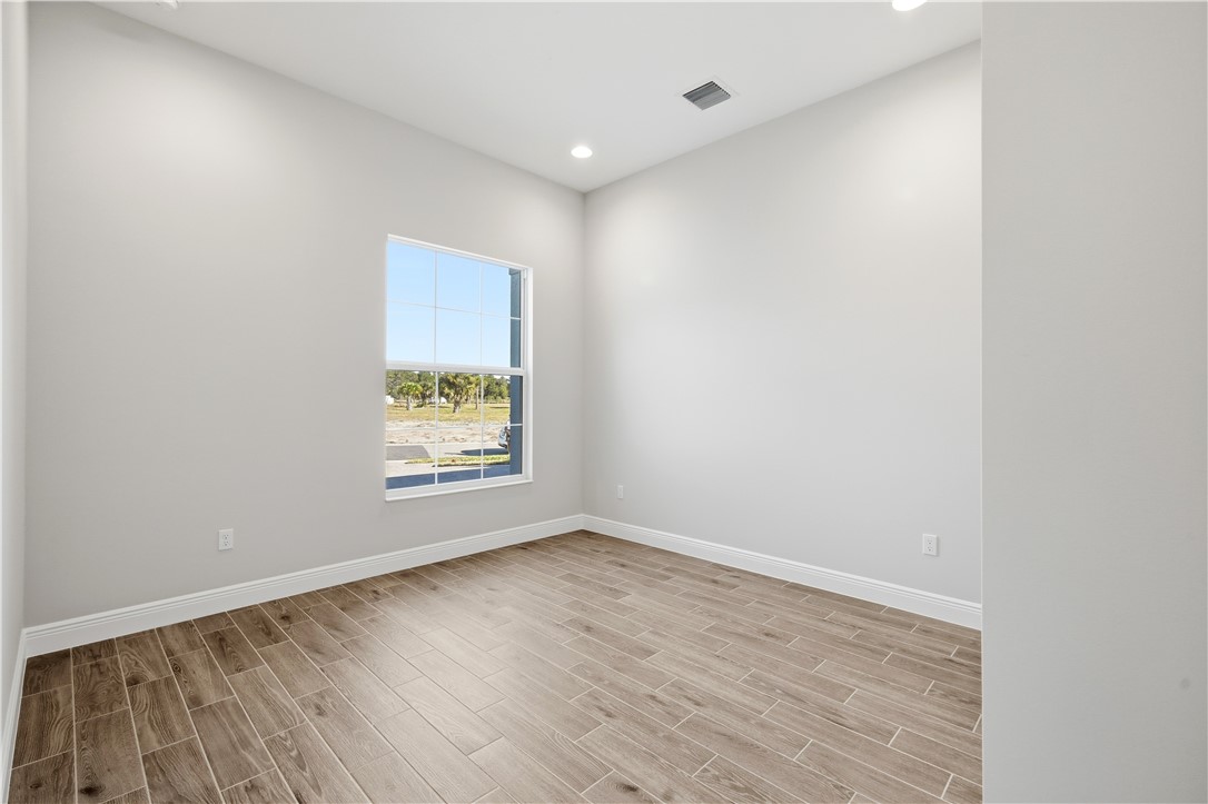 6304 High Pointe Circle Vero Beach, FL 32967 - Photo 18 of 25 an empty room with wooden floor and windows